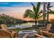 Scenic waterfront view from a backyard featuring a cozy fire pit and comfortable seating by a private dock at 1402 Tangier Way, Sarasota, FL 34239