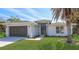 Charming single-story home with a well-manicured lawn, a gray garage door, and a modern front door at 1471 Palmwood Dr, Sarasota, FL 34232