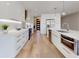 Modern white kitchen with stainless steel appliances, pendant lighting, and hardwood floors at 1471 Palmwood Dr, Sarasota, FL 34232