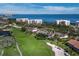 Scenic aerial view of the property with its tan roof set alongside a golf course, lake and ocean with city views at 2065 Harbour Links Dr # 5, Longboat Key, FL 34228