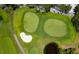 Aerial view of two golf course putting greens, sand trap, and water hazard with trees at 2065 Harbour Links Dr # 5, Longboat Key, FL 34228