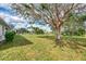 Expansive backyard with mature tree, lush lawn, and view of screened in pool at 26052 Salonika Ln, Punta Gorda, FL 33983