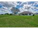 Large, grassy backyard with an expansive view of the home's rear exterior and blue skies at 26052 Salonika Ln, Punta Gorda, FL 33983