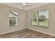 Cozy bedroom features wood flooring, a ceiling fan, and bright windows at 26052 Salonika Ln, Punta Gorda, FL 33983