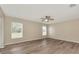 Spacious bedroom features wood floors, a ceiling fan, and two bright windows overlooking the lawn at 26052 Salonika Ln, Punta Gorda, FL 33983