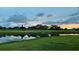 Backyard scene featuring golf course and pond, all reflecting a colorful sunset and cloudy sky at 4060 Penshurst Park, Sarasota, FL 34235