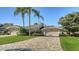 Home featuring a paved driveway and two-car garage, framed by palm trees and manicured landscaping at 4060 Penshurst Park, Sarasota, FL 34235