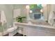 Charming bathroom with marble countertop, white cabinets, modern fixtures, a round mirror, and black hexagon tile at 422 Burns Ct, Sarasota, FL 34236