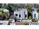 Charming white stucco home with a low wall, xeriscaping, gated entry, and lush tropical plants at 422 Burns Ct, Sarasota, FL 34236