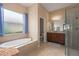 Bathroom offers a large soaking tub under a window, plus walk-in shower, vanity with storage, and tile flooring at 5040 Lake Overlook Ave, Bradenton, FL 34208