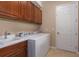 Well-equipped laundry room features white washer, dryer, sink, tile floor and wooden cabinets at 5040 Lake Overlook Ave, Bradenton, FL 34208