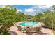 Outdoor pool area featuring lounge seating on a brick patio surrounded by tropical foliage and manicured landscaping at 5135 Riverwood Ave, Sarasota, FL 34231
