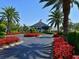 Beautifully landscaped grounds leading to the clubhouse entrance with manicured hedges and bright red flowers at 6501 Stone River Rd # 205, Bradenton, FL 34203