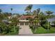 Bright and welcoming home with a two-car garage, manicured lawn, and mature palm trees at 691 Linley St, Longboat Key, FL 34228