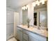 Bright bathroom featuring double sinks, a shower with decorative curtain, and white tiled walls at 128 Sequoyah Dr, Port Charlotte, FL 33954