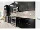 Modern kitchen featuring stainless steel appliances, a mosaic backsplash, and sleek dark cabinetry at 13038 Prima Dr, Bradenton, FL 34211