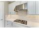 Modern kitchen cooktop with stainless steel range hood and stylish backsplash at 15209 Montello Way, Bradenton, FL 34211