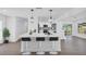 Modern white kitchen with breakfast bar, pendant lighting, quartz countertops, and stainless steel appliances at 1950 Fairview Dr, Englewood, FL 34223