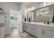 Modern bathroom with double vanity, white countertops, and an open doorway to the bedroom with a mounted TV at 2505 Boone Ct, Sarasota, FL 34237