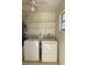 Neat laundry area with a white washer and dryer set, overhead storage shelves, and neutral wall paint at 2607 Woodgate Ln # K9, Sarasota, FL 34231
