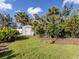 View of backyard with well-maintained lawn, lush greenery, and a storage shed against a blue sky with fluffy clouds at 333 Bayshore Dr, Venice, FL 34285