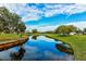 Scenic view of a serene pond reflecting the sky, with lush green surroundings and distant homes at 4306 Presidential Avenue E Cir, Bradenton, FL 34203