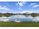 View of a pond reflects community homes with lush grass in the foreground, creating a serene and picturesque setting at 4793 Antrim Dr, Sarasota, FL 34240