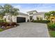 Beautiful exterior of the home with landscaping, a paver driveway, and a black two-car garage door at 5074 Surfside Cir, Bradenton, FL 34211