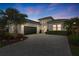 Beautiful home exterior featuring a paver driveway, manicured landscaping, and a dark garage door at 5074 Surfside Cir, Bradenton, FL 34211