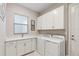 Laundry room features white cabinets, sink, window, and modern washer and dryer at 5074 Surfside Cir, Bradenton, FL 34211