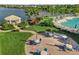 A community pool with lounge seating, tables with umbrellas, and a gazebo overlooking a serene lake surrounded by lush landscaping at 5907 Guarino Dr, Sarasota, FL 34238