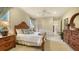 This bright bedroom features a wooden bed frame, plush bedding, ceiling fan, and neutral decor at 7028 Lacantera Cir, Lakewood Ranch, FL 34202