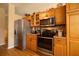 Close-up of kitchen appliances, including stainless steel refrigerator, microwave, and oven with wood cabinetry at 7113 91St E St, Palmetto, FL 34221
