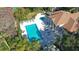 Aerial view of the pool area with lush greenery and palm trees surrounding the pool and clubhouse at 850 S Tamiami Trl # 301, Sarasota, FL 34236