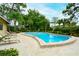 Community pool surrounded by lush landscaping and a brick paved patio and lounge chairs at 966 La Costa Cir # 1, Sarasota, FL 34237