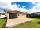 Rear view of the home showcasing a brick patio, screened-in porch, and well-maintained lawn at 11679 Renaissance Blvd, Venice, FL 34293