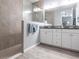 Modern bathroom with a walk-in shower, white double sink vanity, and gray plank flooring at 11679 Renaissance Blvd, Venice, FL 34293