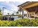 Community pool featuring mature palms and lush landscaping, surrounded by tables with umbrellas at 11679 Renaissance Blvd, Venice, FL 34293