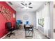 Well-lit home office featuring two desk areas, a ceiling fan, and bright red accent wall at 11679 Renaissance Blvd, Venice, FL 34293
