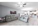 Spacious living room with tile floors, gray sofa set, and an open layout leading to the kitchen at 11679 Renaissance Blvd, Venice, FL 34293