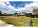 Lush green playground area featuring mature trees, a black bike and a nearby walking trail at 11679 Renaissance Blvd, Venice, FL 34293
