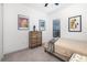 Cozy bedroom with neutral tones, featuring a wooden dresser, a large window and framed artwork on the walls at 15520 Castle Park Ter, Lakewood Ranch, FL 34202