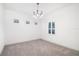 A bright, carpeted room with a modern chandelier and multiple windows with shutters at 15520 Castle Park Ter, Lakewood Ranch, FL 34202
