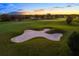 Scenic view of a lush green golf course featuring a sand trap and surrounding trees at 15520 Castle Park Ter, Lakewood Ranch, FL 34202