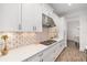 Bright kitchen showcasing white cabinetry, stainless steel appliances, mosaic backsplash, and quartz countertops at 15520 Castle Park Ter, Lakewood Ranch, FL 34202