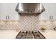 Close up of stainless steel range hood, quartz counters and decorative backsplash at 15520 Castle Park Ter, Lakewood Ranch, FL 34202