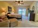 Relaxing main bedroom with a cozy seating area, slider doors to the patio, and serene water view at 1842 Country Meadows Ct, Sarasota, FL 34235