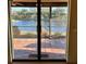 View from inside looking out through sliding glass doors to brick patio and lake at 1842 Country Meadows Ct, Sarasota, FL 34235