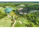 Picturesque aerial view of a golf course, clubhouse, and surrounding green landscape with a lake at 19424 Ganton Ave, Lakewood Ranch, FL 34202