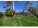 Lush backyard featuring a well-manicured lawn, tropical plants, and an enclosed screened patio at 19424 Ganton Ave, Lakewood Ranch, FL 34202
